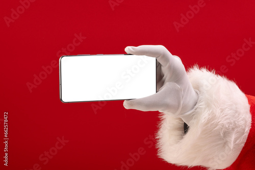 Santa claus holding smattphone with copy space on red background photo