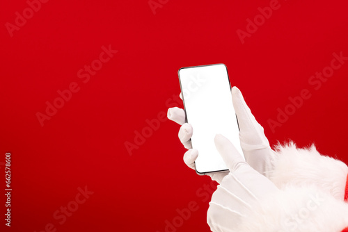 Santa claus holding smattphone with copy space on red background photo