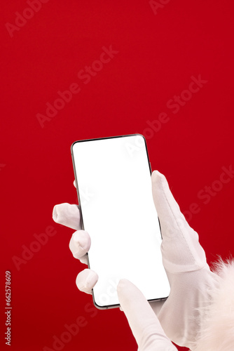 Vertical image of santa claus holding smattphone with copy space on red background photo