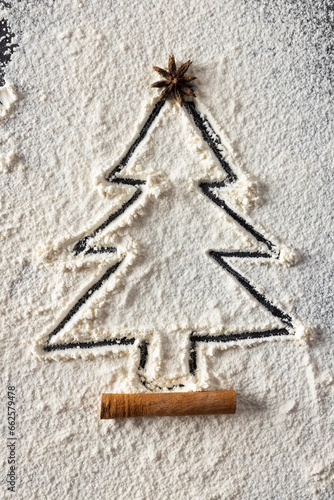 Vertical image of anis seed and christmas tree shape in flour with copy space on black background