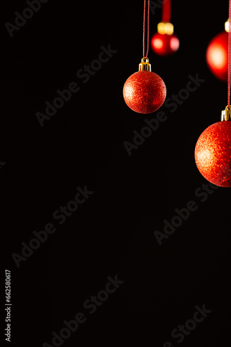Vertical image of red christmas baubles with copy space on black background