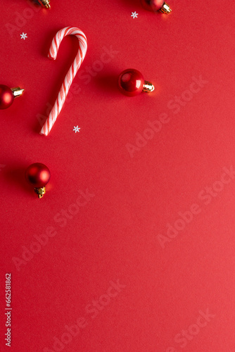 Vertical image of christmas baubles decorations and candy canes with copy space on red background