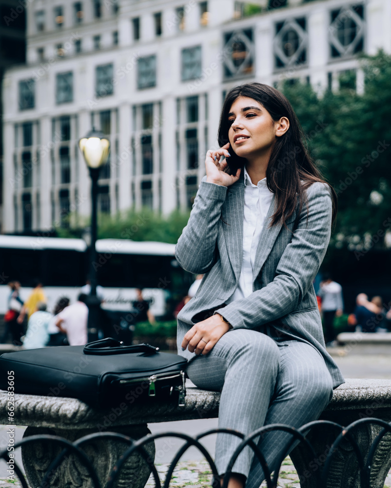 Businesswoman sitting on bench and speaking on phone