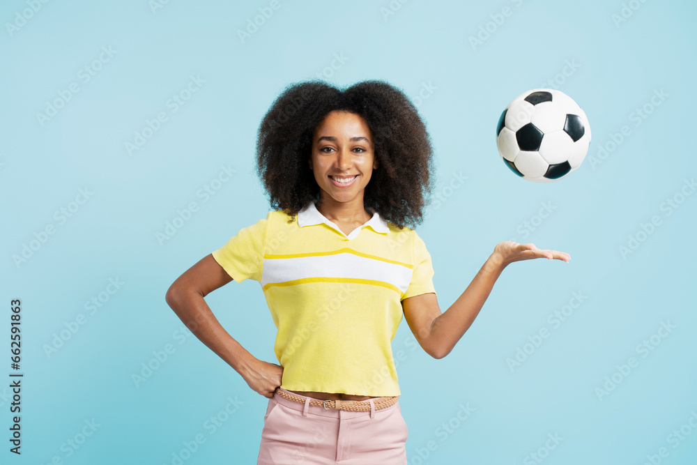 Confident African American woman with curly hair holding soccer ball looking at camera Confident African American woman with curly hair holding soccer ball looking at camera