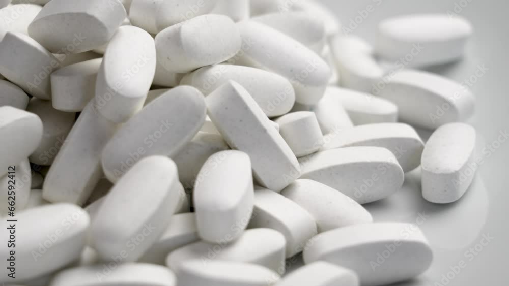 Elongated medical pills spilled on white ceramic background. Rotation Elongated medical pills spilled on white ceramic background. Rotation