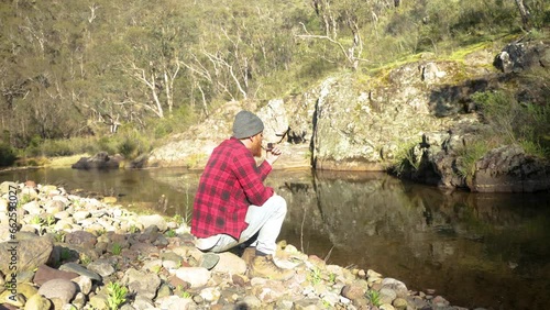 A bushman smokes a pipe by a river in the Victorian High Country. photo