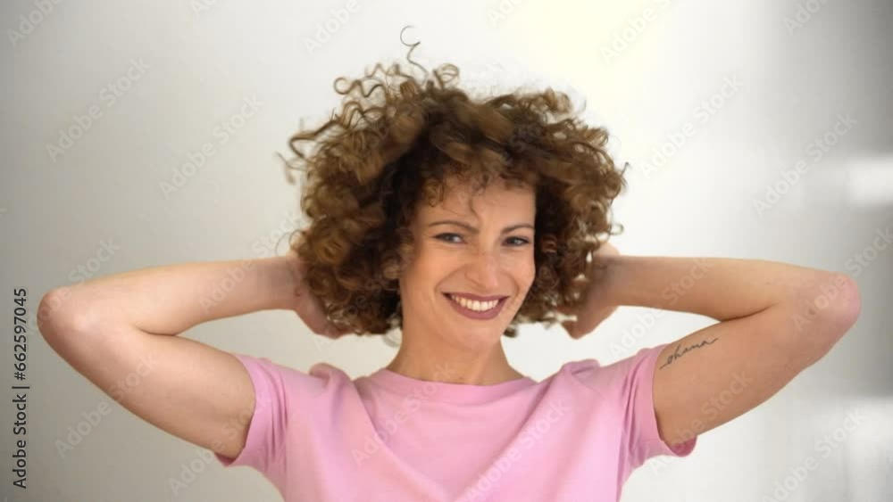 Positive young woman playing with her hands in her curly afro hair Positive young woman playing with her hands in her curly afro hair