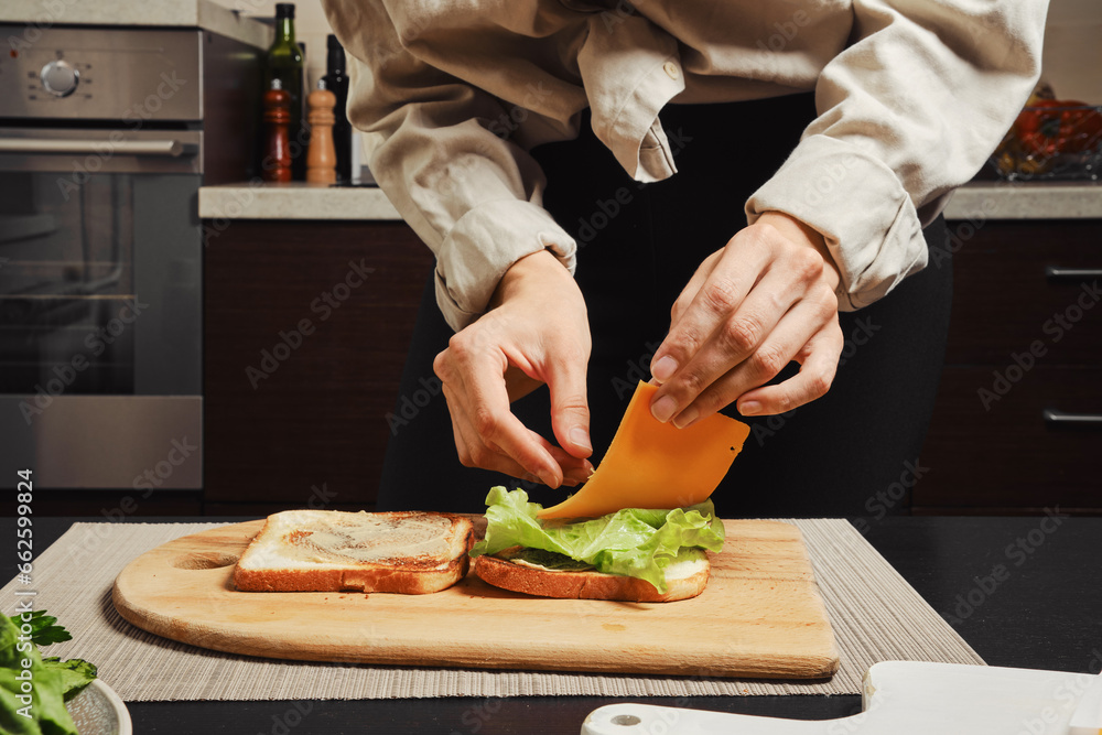 Unrecognizable woman makes sandwich with cheese