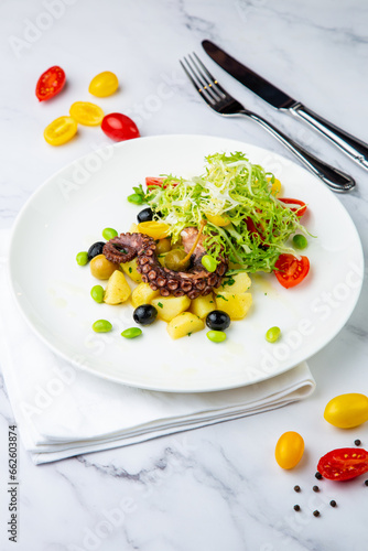 salad with olives, herbs, cherry tomatoes, potatoes and octopus tentacles side view