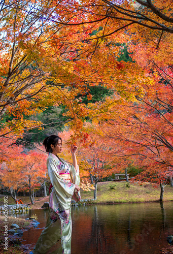 portrait of young asian girl traveller in traditional kimino dress standing holding meple leavse in the autumn leaves season at the public park in japan, photo