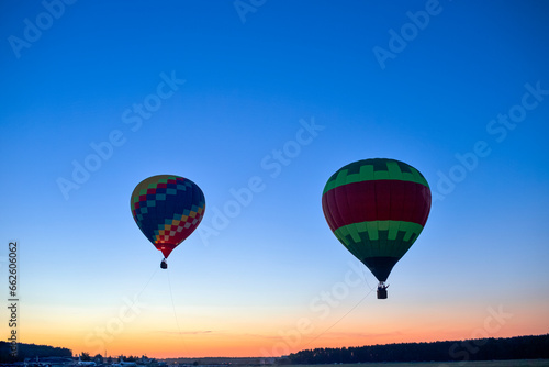 Colorful Air Balloons Levitating Over the Field Outdoors Against Clear Blue Skies At Twilight.