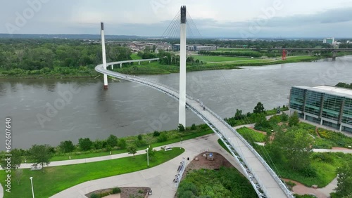 Cable-stayed bridge over a river in Omaha, NE with pedestrian walkways. Riverside park, paths, and greenery nearby. Bob Kerrey Pedestrian Bridge over Missouri River. Aerial establishing shot. photo