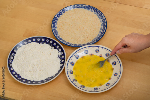 Składniki na panierkę na talerzach - mąka, bułka tarta i jajko