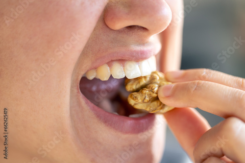 Detailed shot of a woman bites walnut.