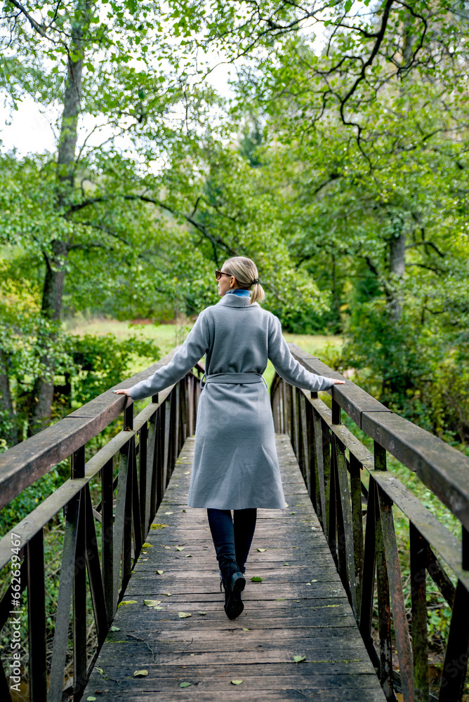 Fototapeta premium Girl with elegant coat walking on the bridge looking to the left
