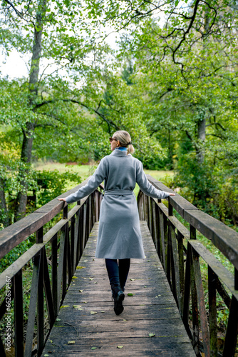 Girl with elegant coat walking on the bridge looking to the left