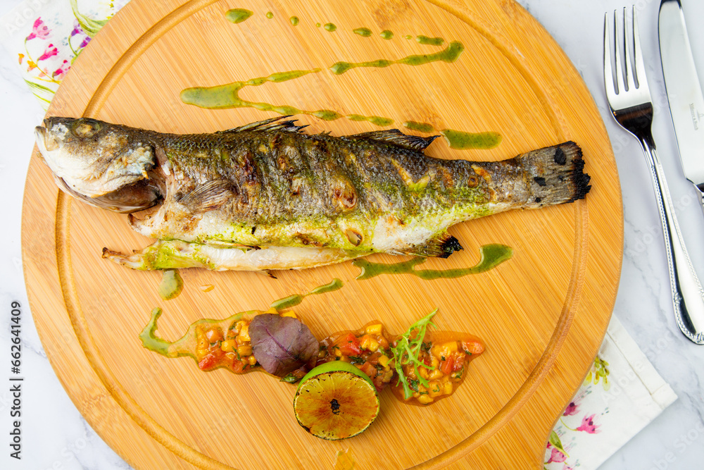 baked fish with spices and lemon on a wooden tray side view baked fish with spices and lemon on a wooden tray side view