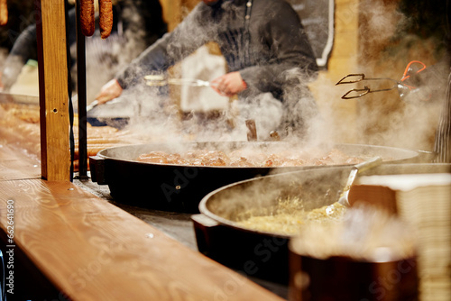 Process of cooking street food outdoors. Frying pan with fried dishes. Christmas Fair at Wroclaw main square