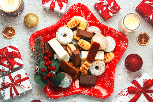 Top view of Nougat christmas sweet,mantecados and polvorones with christmas ornaments on a christmas star shaped red plate. Assortment of christmas sweets typical in Spain photo