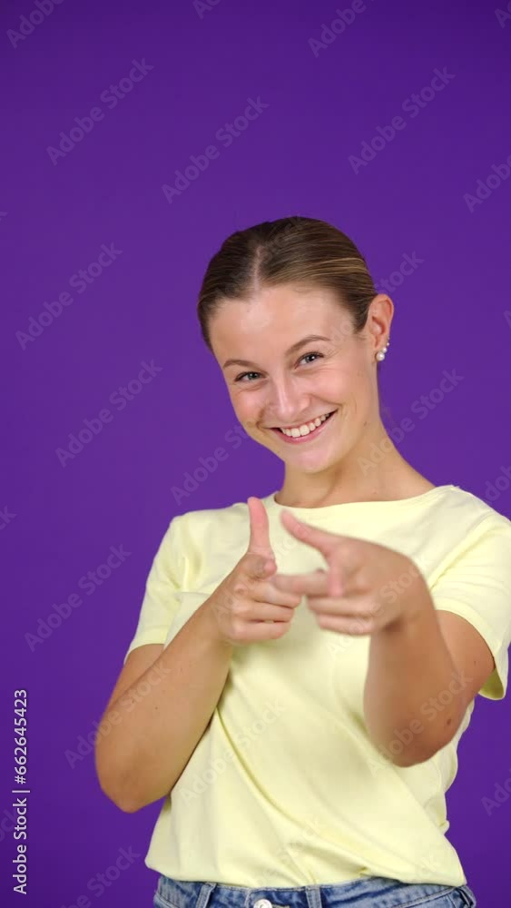 Young woman calling attention of spectator and pointing at camera isolated on purple background. Young woman calling attention of spectator and pointing at camera isolated on purple background.