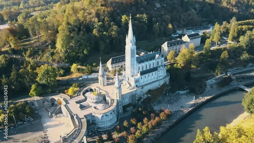 Aerial tilting establishing shot of the Lourdes Cathedral with tourists outside photo