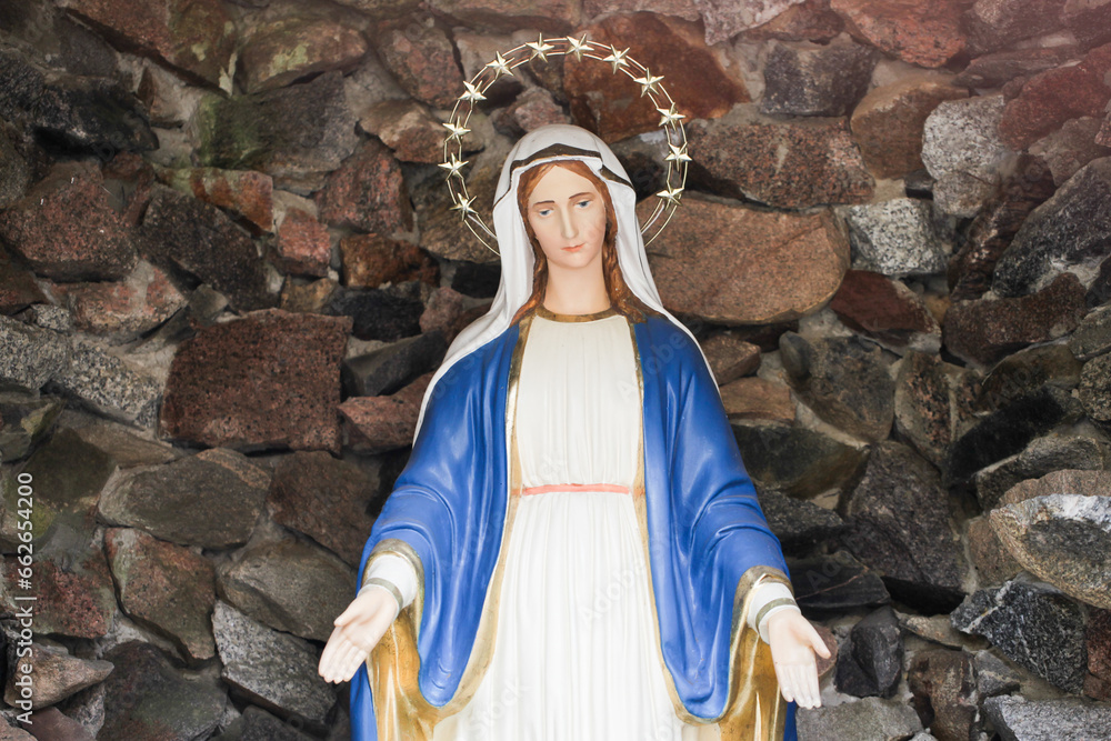 Statue of Virgin Mary with stars aureole. Mother Marry in stone cave