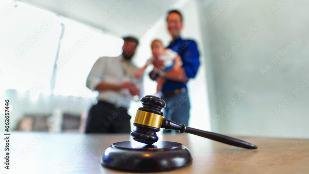 On the first plan a hammer of justice, in the blurry background two men with a baby. Generative AI On the first plan a hammer of justice, in the blurry background two men with a baby. Generative AI