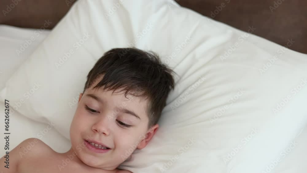 portrait of cute kid boy lying on bed under blanket,talking on old phone,relax playing with sheet.sunshine from window,smiling child trying to sleep,take a nap daytime.4k portrait of cute kid boy lying on bed under blanket,talking on old phone,relax playing with sheet.sunshine from window,smiling child trying to sleep,take a nap daytime.4k