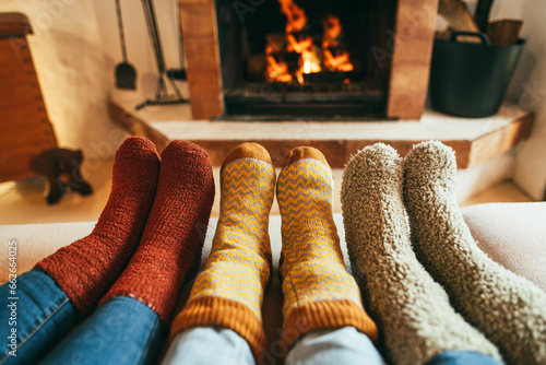 Legs view of happy family wearing warm socks in front of fireplace - Winter, love and cozy concept - Focus on center and left socks