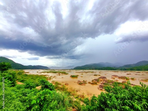 Big and small rocks in the brown river Against the backdrop of a gray sky.