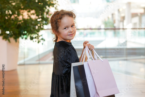 Child girl with shopping bags walking in shopping mall