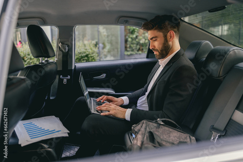 Businessman working on laptop sitting car backseat on the way to office. High quality photo © Yaroslav Astakhov
