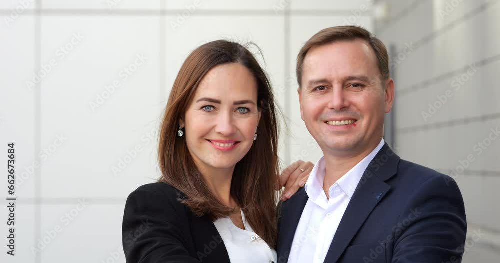 Happy married couple in suits stands embracing together and shows key to new apartment. New apartment owners together show key with happiness Happy married couple in suits stands embracing together and shows key to new apartment. New apartment owners together show key with happiness