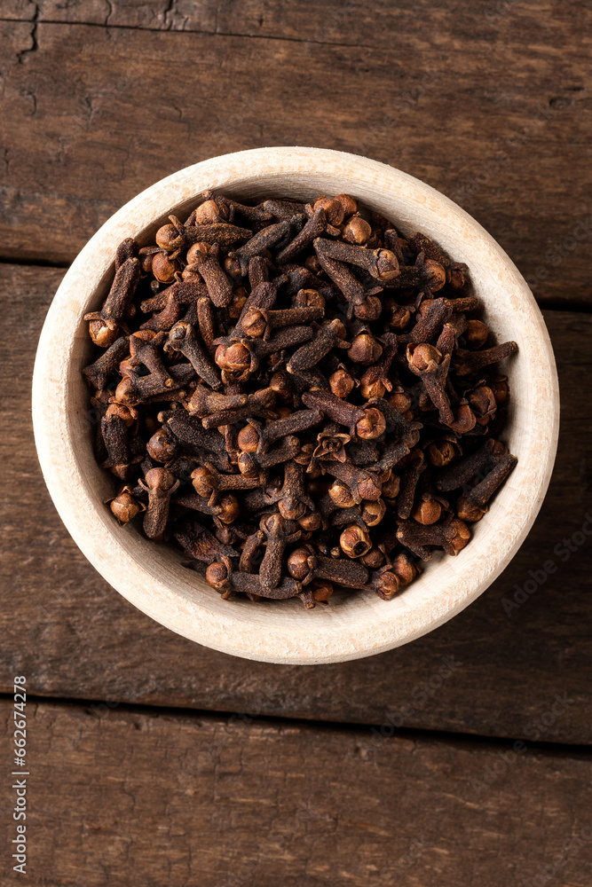 Dried cloves in bowl on wooden table. Close up. Top view Dried cloves in bowl on wooden table. Close up. Top view