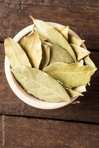 Dried bay leaves in bowl on wooden table. Close up. Top view