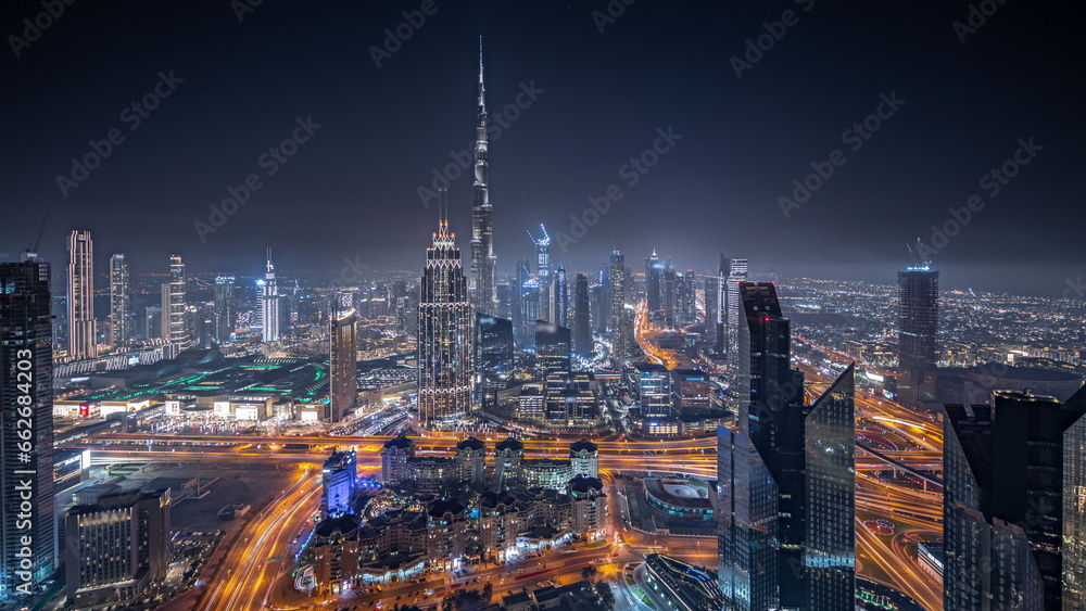 Panorama showing aerial view of tallest towers in Dubai Downtown skyline and highway night timelapse.