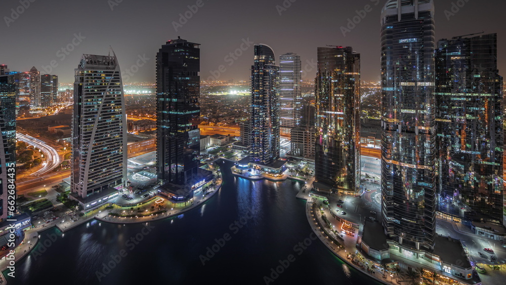 Naklejka premium Tall residential buildings at JLT aerial night timelapse, part of the Dubai multi commodities centre mixed-use district.