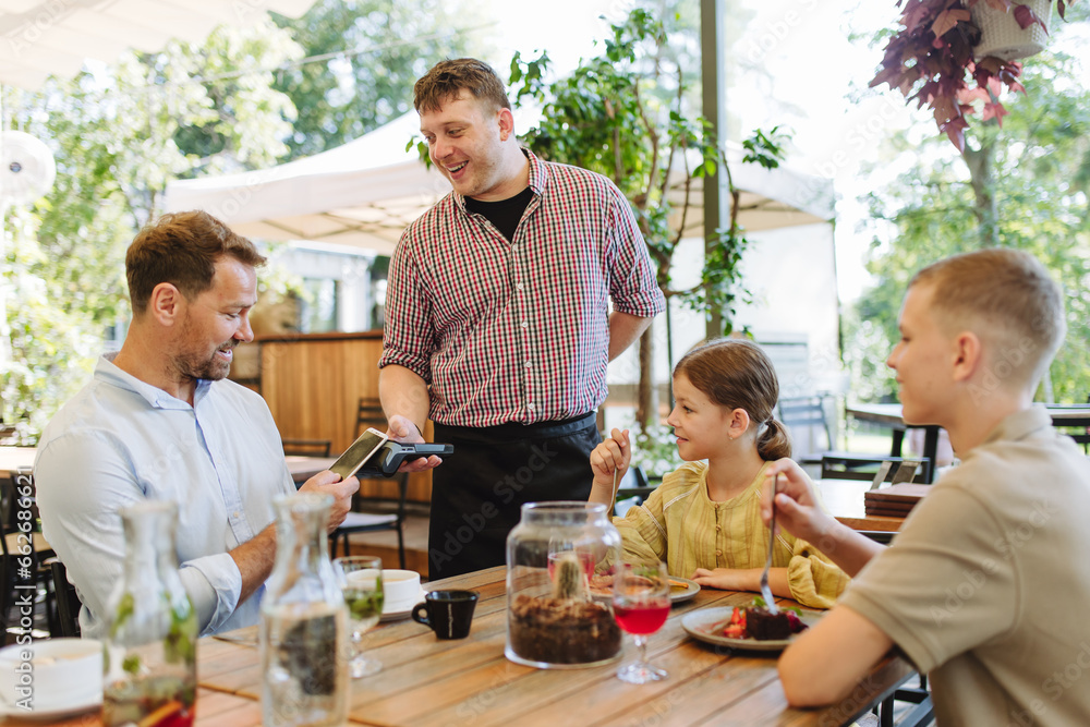 Father and children ordering food from waiter. Single-parent family having dinner at restaurant. Concept of Father's Day. Father and children ordering food from waiter. Single-parent family having dinner at restaurant. Concept of Father's Day.