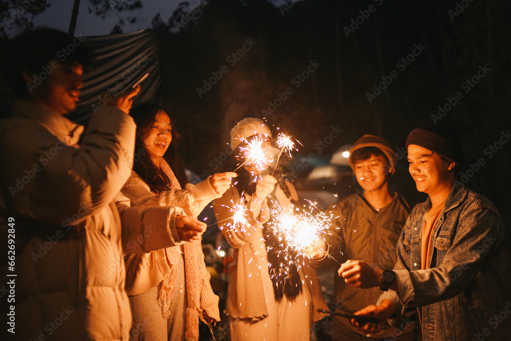 Group of multiethnic friends holding sparklers with happy expression. Young men and women enjoying out with fireworks.