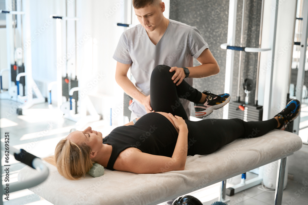 Expectant mother during manual therapy session lies on massage table Expectant mother during manual therapy session lies on massage table