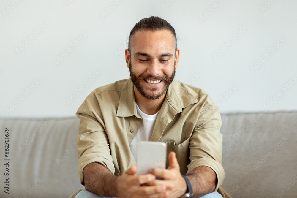 Great Mobile Application. Happy Young Man Using Phone At Home Great Mobile Application. Happy Young Man Using Phone At Home