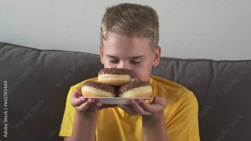 Hungry boy licks his lips and smiles while looking at delicious chocolate donuts Hungry boy licks his lips and smiles while looking at delicious chocolate donuts