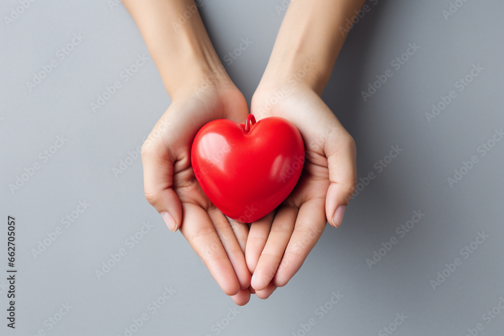 Obraz premium Two hands tenderly holding a vibrant red heart, symbolizing the profound and compassionate connection between individuals in a simple yet powerful gesture of love and care. Ai generated