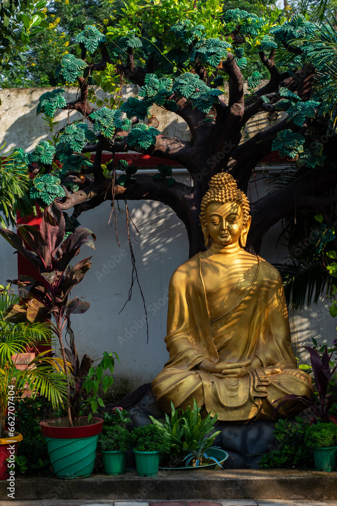 Large pile of garbage dumped at the side of the road with plastic container and paper boxes.Beautiful golden statue of Lord Buddha at Topchachi.