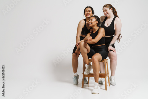 Three positive women with different body types posing together isolated over white background