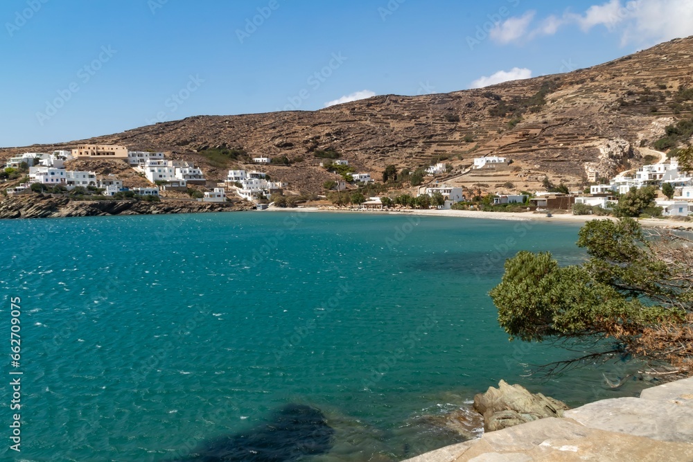 Idyllic beach scene with a white-washed row of buildings on the shore of a tranquil blue bay