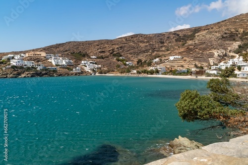Idyllic beach scene with a white-washed row of buildings on the shore of a tranquil blue bay