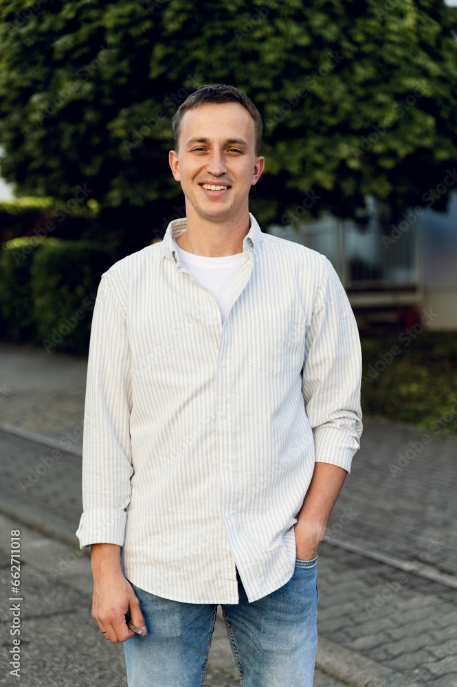 portrait of a satisfied middle-aged man outside. guy in a shirt and jeans smiles portrait of a satisfied middle-aged man outside. guy in a shirt and jeans smiles