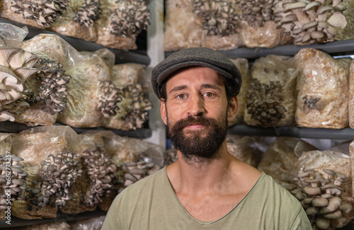 Portrait of the owner of the oyster mushroom farm. young man looking directly to the camera against the background of roduction blocks of oyster mushrooms photo