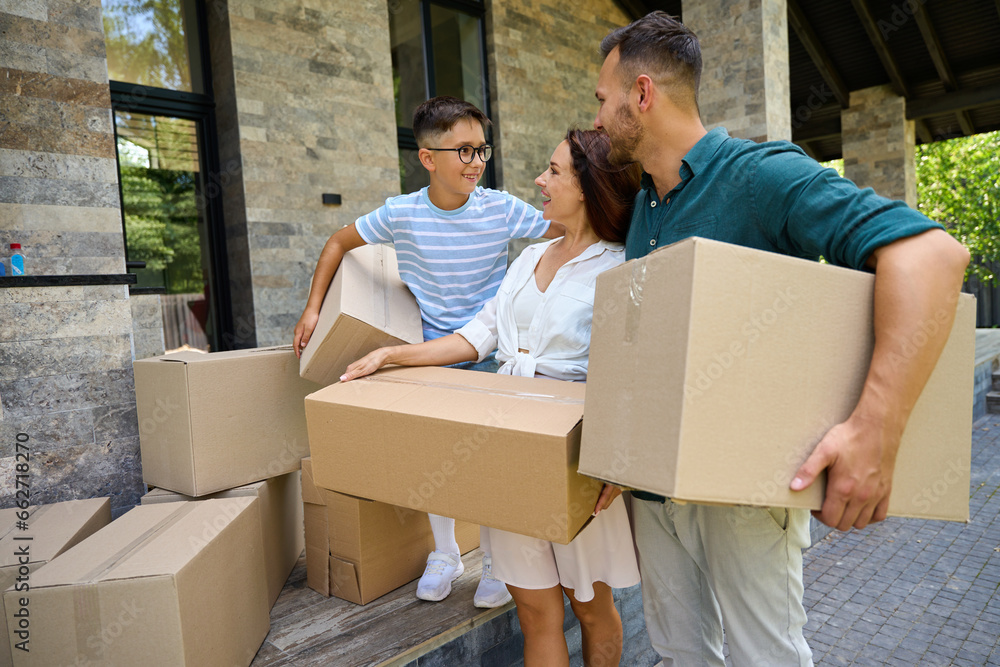 Boy helps his parents carry boxes of things Boy helps his parents carry boxes of things